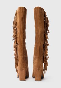 Brown suede knee-high boots with fringe detailing along the sides, square heels, and a smooth texture. Vertical stitching visible on the front.