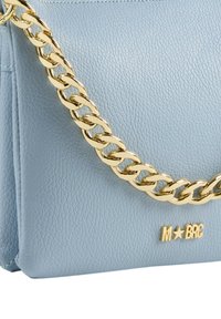 Borsa a tracolla in pelle blu chiaro con catena dorata e logo in rilievo "M★BRG". La superficie è texturizzata con cuciture visibili.
