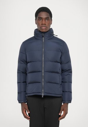 Navy blue puffer jacket with a high collar, front zipper, and quilted design. Smooth fabric with horizontal stitching and minimal hardware.