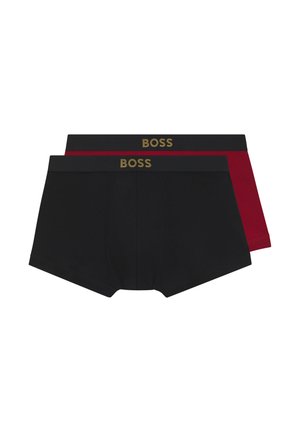 Mand uden skjorte stående med fronten mod kameraet iført tætsiddende sorte boxer briefs med guld "BOSS" logo på linningen på hvid baggrund.