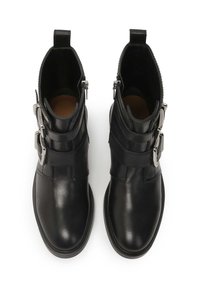 Botas de tobillo de cuero negro con dos hebillas ajustables, textura suave, punta redondeada y cremalleras laterales para un fácil uso.