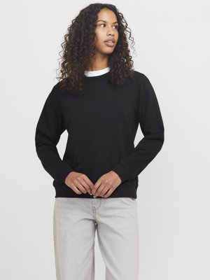 Zwarte sweatshirt met lange mouwen, geribbelde manchetten en zoom, met een ronde hals. Combinatie met lichtgrijze jeans. Eenvoudig ontwerp en textuur.
