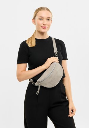 Gray suede fanny pack with a rounded shape, zipper closure, and adjustable strap featuring branding, worn on the body.