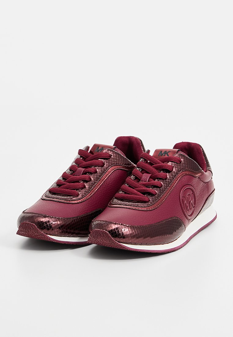 Un paio di sneaker bordeaux di Michael Kors con accenti metallici testurizzati, design con lacci e logo del marchio laterale su sfondo bianco.