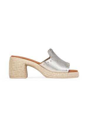 Mule de cuero plateado con puntera abierta, tacón de bloque envuelto en yute y detalle de tachuelas metálicas en la parte superior.