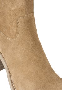 Tan suede boot with visible stitching detail and stacked heel, cropped on a white background.