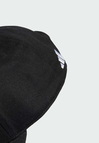 Gorra negra hecha de tejido texturizado con un visor curvado, que presenta un logotipo gris en el costado. El diseño es simple y aerodinámico.