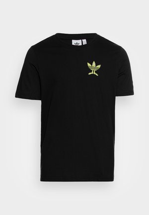 Camiseta negra de manga corta con un pequeño logo de hoja de dibujos animados amarillo-verde con ojos y piernas en el lado izquierdo del pecho.