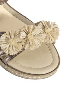 Bronzefarbene Leder-Sandale mit drei dekorativen cremefarbenen Strohhosen, einem gepolsterten beigen Fußbett und einer strukturierten geflochtenen Sohle.