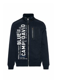 Felpa marina con alto collo, chiusura con zip e tasca sul petto sinistro. Presenta testo stampato in bianco e blu e dettagli del logo sulla parte anteriore.