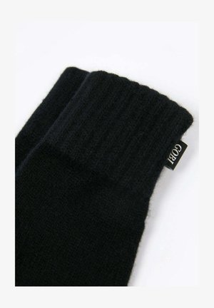 Schwarze gestrickte Wollhandschuhe mit gerippten Bündchen und einem kleinen Stoffetikett an der Seite.