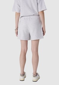Szare bawełniane szorty z elastycznym pasem, z surowym dołem. Noszone z białymi trampkami i subtelnymi srebrnymi akcesoriami.