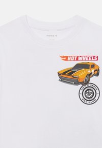 Balta medvilnė marškinėliai su oranžine sportinio automobilio grafika, juodomis grietelėmis, tekstu "HOT WHEELS" ir apvaliu "CAR CLUB" logotipu.