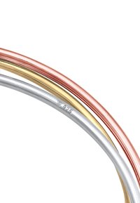 Tre anelli intrecciati in oro rosa, oro giallo e argento. Ogni fascia è liscia con una finitura lucida e riportata con la scritta "925."