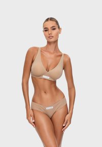 Beżowy zestaw bikini z trójkątnym stanikiem o szerokich ramiączkach oraz dopasowanymi majtkami typu low-rise, wykonany z gładkiego, elastycznego materiału. Widoczna metka marki.