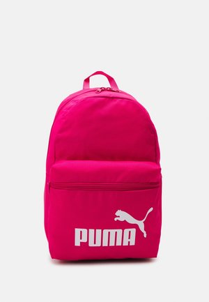 Jasnoróżowy plecak z przednią kieszenią na zamek i białym logo Puma przedstawiającym skaczącego pumę na jednolitym jasnoszarym tle.