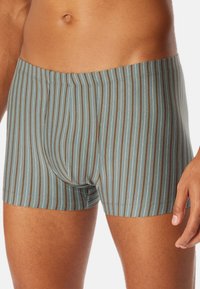 Männer Boxershorts aus blau-grauem Stoff mit vertikalen Streifen in Braun und Creme. Weicher, elastischer Bund. Figurbetontes Design mit kurzen Beinen.