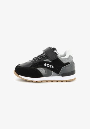 Baskets pour enfants noires, grises et blanches avec des lacets, une bride Velcro et le mot "BOSS" sur le côté, vues de l'extérieur.
