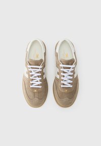 Καφέ σουέντ αθλητικά παπούτσια με λευκές δερμάτινες λεπτομέρειες, διαθέτουν λευκά κορδόνια, στρογγυλεμένη μύτη και σόλα από καουτσούκ τύπου gum. Χρυσή λεπτομέρεια λογότυπου στο πλάι.