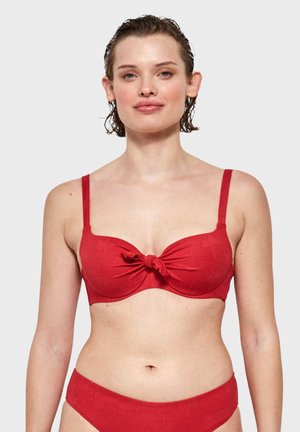 Top de bikini rojo con detalle de frente retorcido, tirantes ajustables y una textura suave. Presenta patrones sutiles en relieve sobre la tela.
