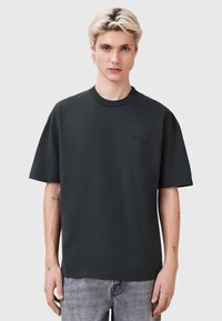 Sort oversized T-shirt i bomuld med rund hals, der har subtilt broderet branding på brystet. Korte ærmer og en afslappet pasform.