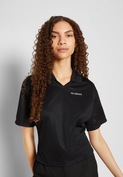 Camisa polo preta de manga curta com um padrão de diamante texturizado, apresentando um decote em V e um discreto detalhe do logo em branco no peito.