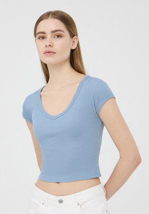 Cropped top azzurro chiaro a maniche corte, con scollatura a V e design aderente, realizzato in tessuto morbido e con una texture liscia.