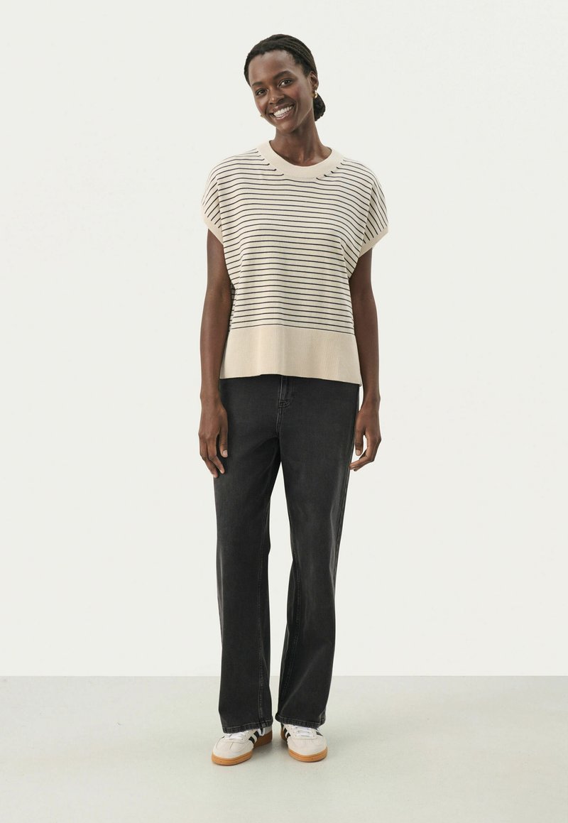 Beige og sort stribet strikket sweater med korte ærmer, parret med høj-taljet sorte jeans og hvide sneakers. Enkel design, afslappet pasform.