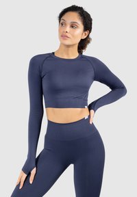 Dunkelblaues, langärmliges, sportliches Crop-Top mit passenden hochgeschnittenen Leggings. Glatte Textur, taillierte Passform und Daumenlöcher an den Ärmeln.