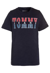 Námorně modré tričko s krátkým rukávem z organické bavlny, s výrazným logem "TOMMY JEANS" v červené, bílé a modré barvě na přední straně.
