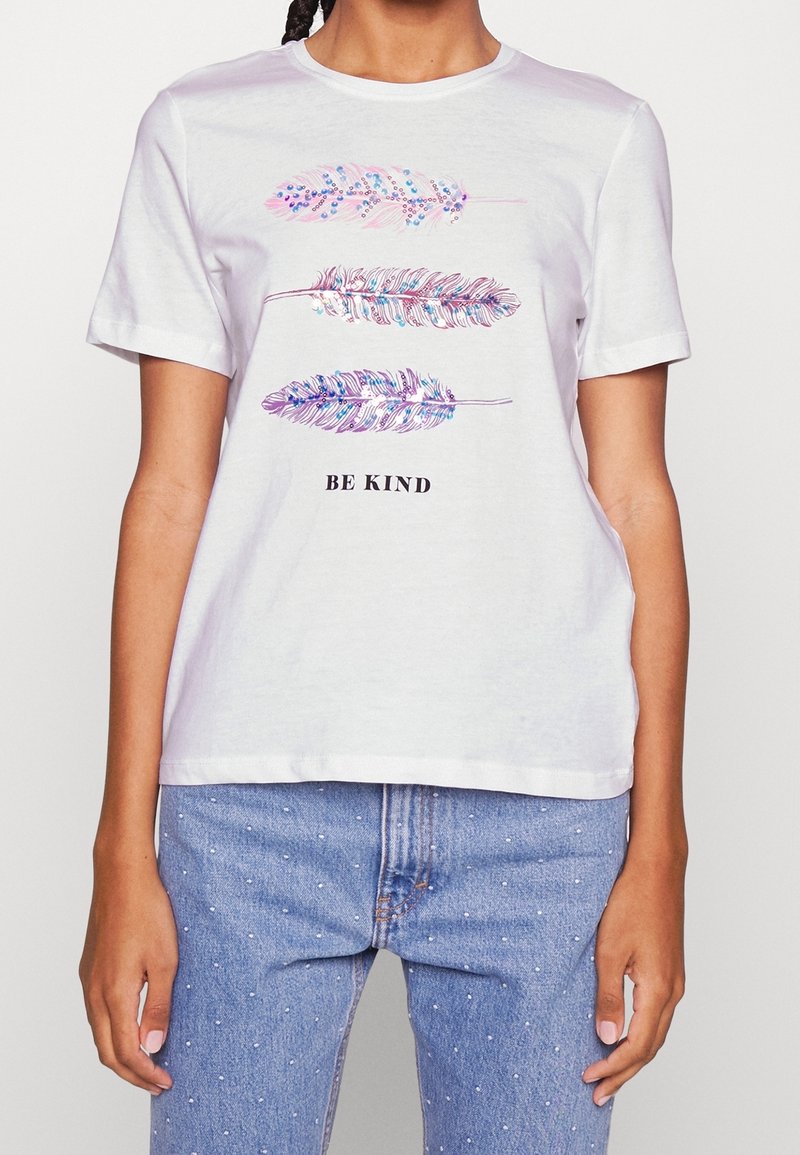 Camiseta de algodón blanca con tres ilustraciones coloridas de plumas y el texto "SE AMABLE" en negro, con cuello redondo y mangas cortas.