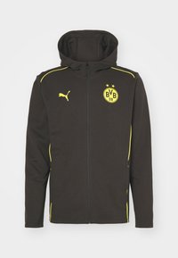 Giacca a zip nera con cappuccio, con logo Puma giallo ed emblema del club calcistico BVB 09, caratterizzata da piping giallo sulle spalle e sui lati.