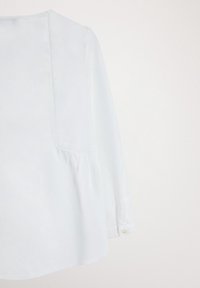 Vaaleansininen pitkähihaiseksi puseroksi, jossa on pyöreä pääntie, laskostettu yksityiskohta vyötäröllä ja nappikiinnitys hihansuissa. Silkkinen kangastekstuuri.