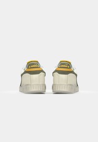 White and grey sneaker with a green and yellow accent. Features textured leather, a rubber sole, and an embroidered logo on the heel.