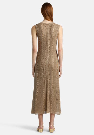 Robe maxi sans manches en tricot beige avec des motifs complexes et un tissu texturé, présentant des rayures verticales et un design en tricot ouvert à l'arrière.