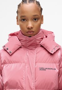 Pink padded jacket with a high collar, glossy texture, snap buttons on the collar, and front pocket featuring the "KARL LAGERFELD JEANS" logo.