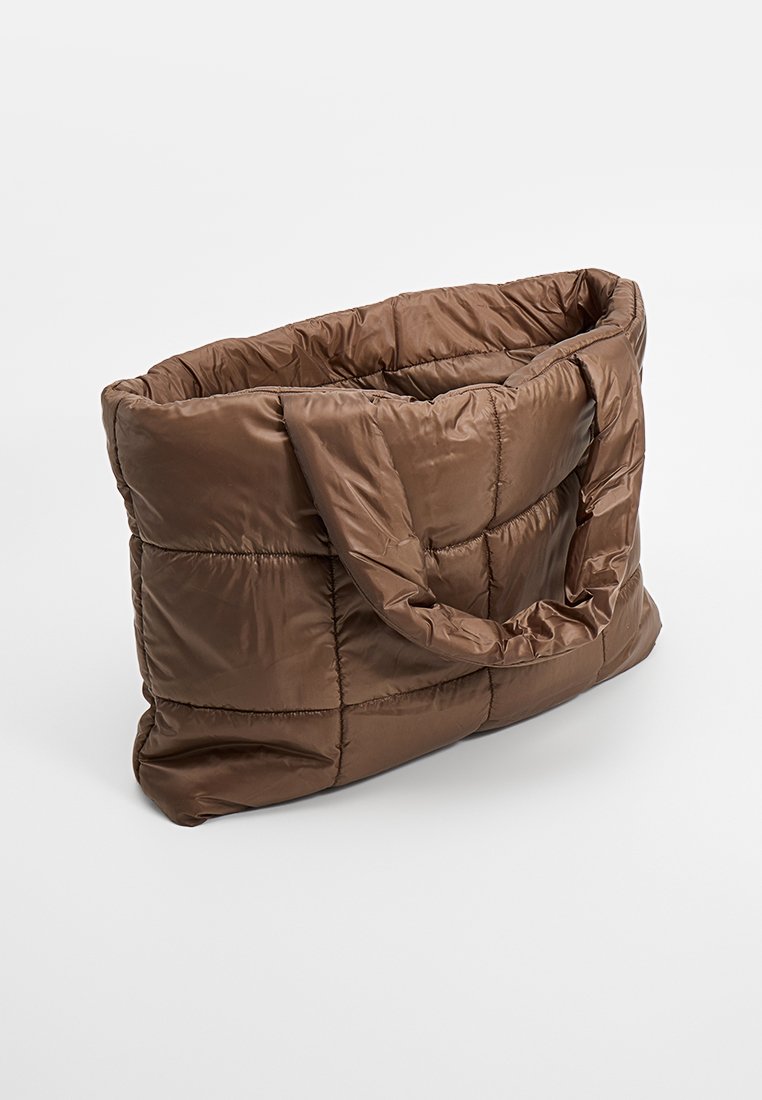 Braune gepolsterte Tragetasche mit gestepptem Muster, zwei stabilen Griffen und einem geräumigen Innenraum. Das Material wirkt weich und leicht glänzend.