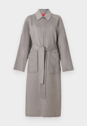 Cappotto in lana grigia con zip frontale, grandi tasche applicate e cintura staccabile. Presenta un colletto appuntito e maniche ampie.
