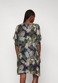 Vestido estilo kimono floral con mangas cortas. Fondo azul marino oscuro con patrones de hojas en verde claro y crema. Tela suave y ligera.