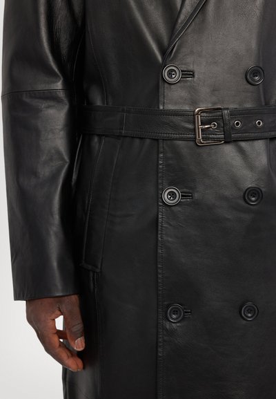 Svart läder trenchcoat med en dubbelknäppt design, stora knappar, midjebälte och mjuka texturer.