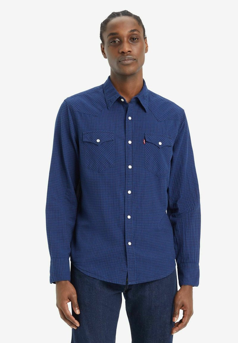 Camisa de manga larga en patrón de cuadros azul marino, con dos bolsillos en el pecho, botones blancos y un diseño de yugo al estilo del oeste.