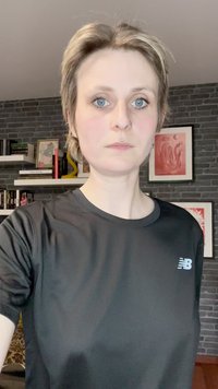 Μαύρη αθλητική μπλούζα φτιαγμένη από ελαφρύ, υλικό που απορροφά την υγρασία. Έχει στρογγυλή λαιμόκοψη και ένα μικρό μπλε λογότυπο New Balance στο στήθος.