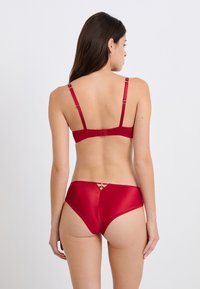 Rotes Satin-BH- und Unterhosenset mit verstellbaren Trägern, einem Hakenverschluss und einem dekorativen Rückenschnellverschluss. Glatte Textur und taillierte Passform.