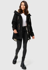 Zwarte parka jas met een fleece voering, verstelbare trekkoorden en bruine accenten. Draag je over een witte top en gecombineerd met donkere jeans en zwarte laarzen.