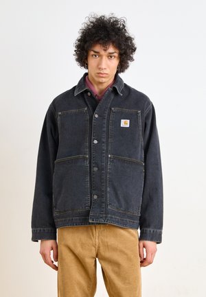 Veste en denim noir avec un col, deux poches avant et fermeture à boutons. Présente des coutures jaunes et un patch de marque sur la poitrine.