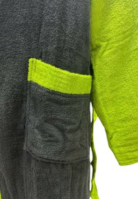 Tessuto di asciugamano nero e verde brillante con superficie testurizzata. Presenta una tasca con un bordo verde abbinato, che indica un design bicolore.