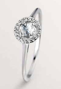 Anillo de plata con una piedra central redonda y clara, rodeada de pequeñas piedras brillantes. Banda suave y pulida con un diseño delicado.