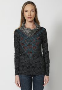 Schwarzes Langarmoberteil mit einem strukturierten Blumenmuster, das farbenfrohe geometrische Stickerei am Kragen und einen Schalkragen aufweist.