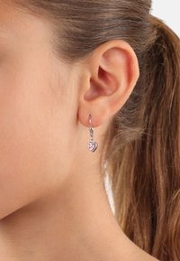 Orecchino a cerchio in argento con pendente a forma di cuore in pietra preziosa rosa, che mette in evidenza metallo lucido e pietre decorative trasparenti.