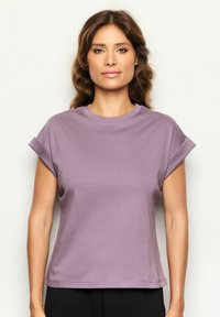 T-shirt a maniche corte, con scollo a giro in tessuto viola chiaro, caratterizzato da maniche arrotolate e una vestibilità rilassata, texture liscia con una leggera elasticità.